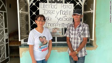Marta and Jorge Perdomo stand in front of a sign on their home in San José de las Lajas, Cuba, on June 28, 2022. 