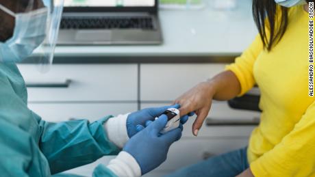 A medical worker examines a female patient with an oximeter device during the coronavirus outbreak.