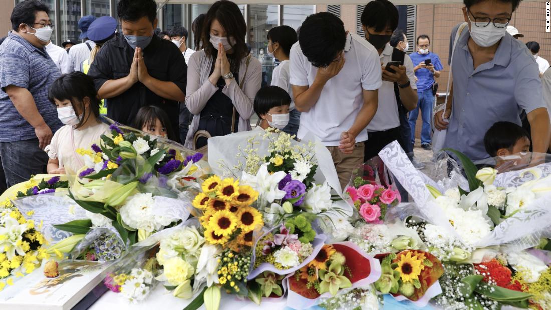 People pray after placing flowers at a makeshift memorial in Nara, Japan, on July 10, near the location where former Japanese Prime Minister Shinzo Abe was fatally shot.