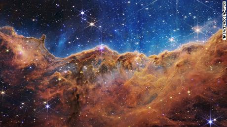 This landscape of &quot;mountains&quot; and &quot;valleys&quot; speckled with glittering stars is actually the edge of a nearby, young, star-forming region called NGC 3324 in the Carina Nebula. Captured in infrared light by NASA&#39;s new James Webb Space Telescope, this image reveals for the first time previously invisible areas of star birth. 