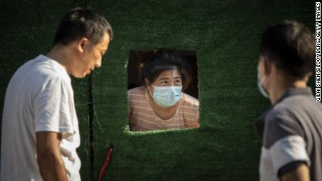 A Shanghai resident peeks through an opening in the barricade surrounding a neighborhood placed under Covid-19 lockdown on July 10.