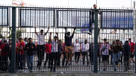 People try to climb gates outside the Stade de France as kick-off is delayed during the 2022 UEFA Champions League Final.
