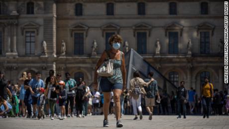 A woman wearing a face mask walks in front of the Louvre Museum in Paris, France, July 8.