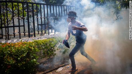 A protester takes cover from a tear gas canister during a protest in Colombo, Sri Lanka, July 13. 