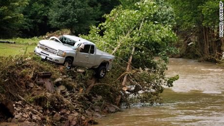 A truck sits on the edge over a river on Thursday after being swept away in a flash flood in Whitewood, Virginia.