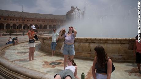 People cool off with a fountain's water during a heat wave in Seville, Spain on July 12.