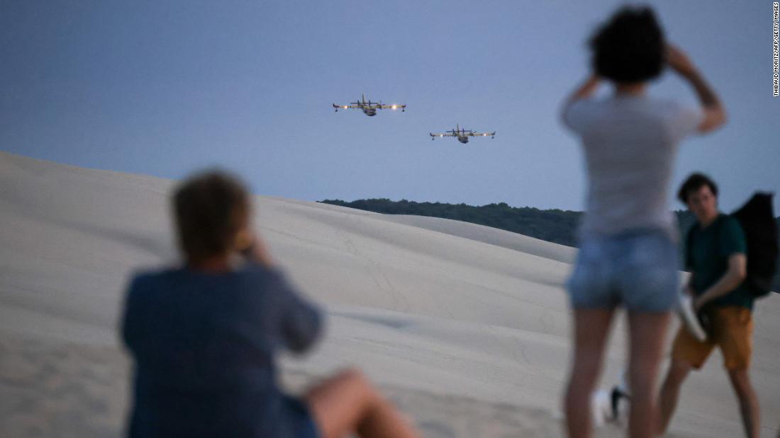 People take pictures of firefighting aircraft flying over La Teste-de-Buch, France, on July 14.