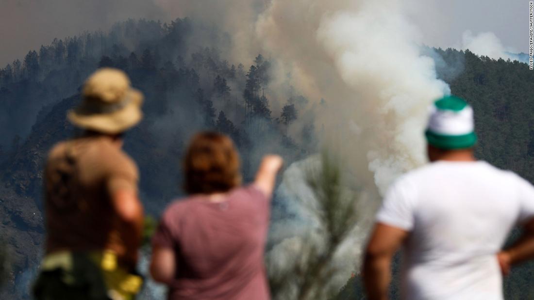Residents watch as a column of smoke emerges from a fire in A Pobra do Brollón, Spain, on July 17.