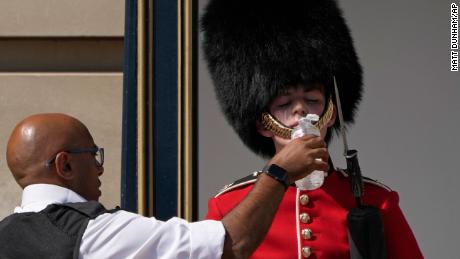 A police officer givers water to a British soldier wearing a traditional bearskin hat, on guard duty outside Buckingham Palace, during hot weather in London, Monday, July 18, 2022. The British government have issued their first-ever &quot;red&quot; warning for extreme heat. The alert covers large parts of England on Monday and Tuesday, when temperatures may reach 40 degrees Celsius (104 Fahrenheit) for the first time, posing a risk of serious illness and even death among healthy people, the U.K. Met Office, the country&#39;s weather service, said Friday. (AP Photo/Matt Dunham)