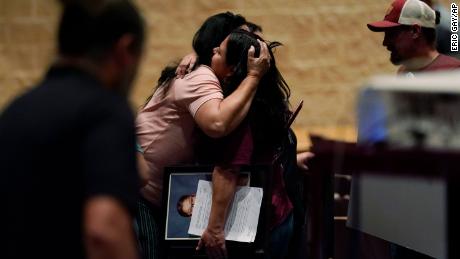 Un membro della famiglia tiene un ritratto della vittima della sparatoria Jackie Casares mentre lo abbracciano dopo una riunione del consiglio di amministrazione lunedì sera a Uvalde.