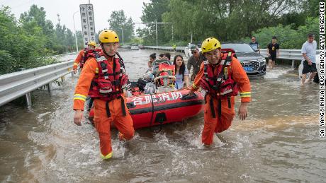 Rescuers help evacuate residents stranded at a highway entrance in Zhengzhou, central China's Henan province, July 23, 2021. 