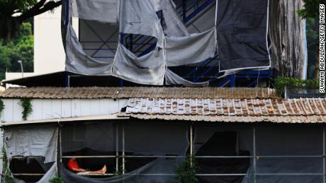 Un lavoratore migrante siede fuori dal suo dormitorio improvvisato in un cantiere edile a Singapore.