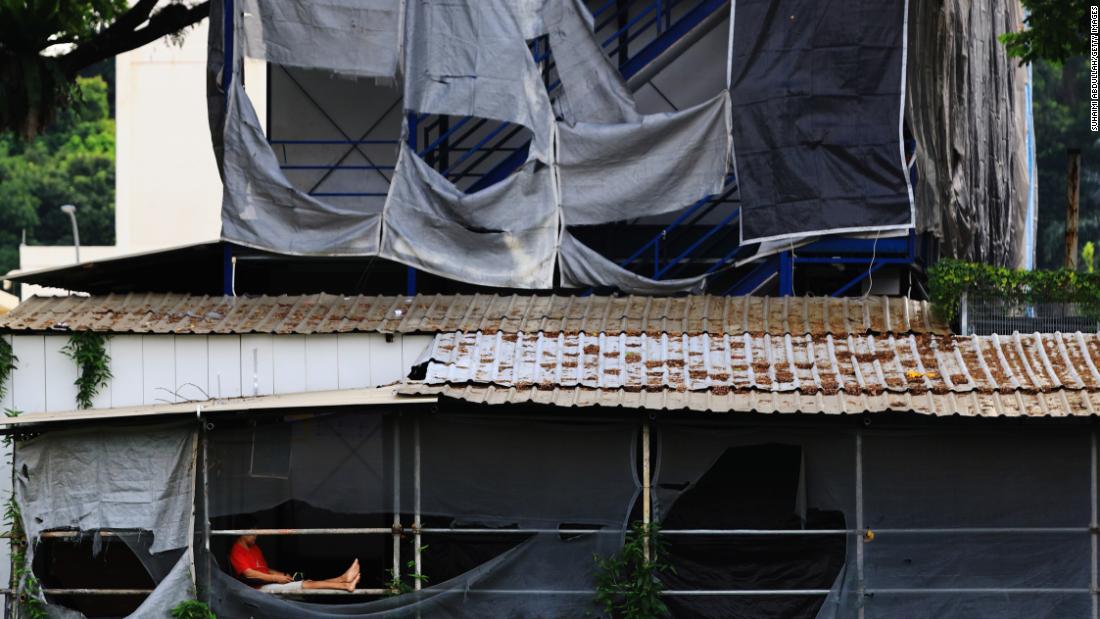 A migrant worker sits outside his makeshift dormitory room at a stalled construction site in Singapore.