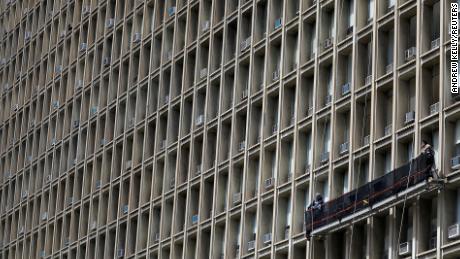 Window cleaners clean a building with rows of air conditioners in New York last April. 