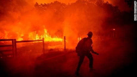 A firefighter runs to put out flames from the Oak Fire in Mariposa County on Friday.