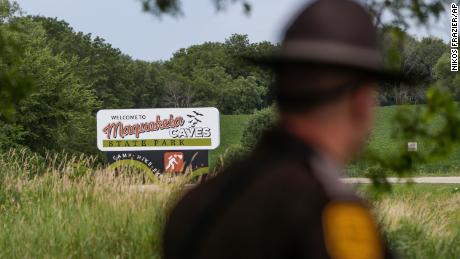 An Iowa State Patrolman walks past a Maquoketa Caves State Park sign as police investigate a shooting that left several people dead on Friday, July 22.