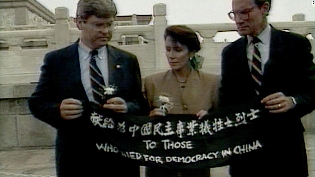 In this image taken from video, Pelosi and fellow US Reps. Ben Jones, left, and John Miller unfold a banner during a trip to Beijing in September 1991. The banner says, &quot;To those who died for democracy in China.&quot;