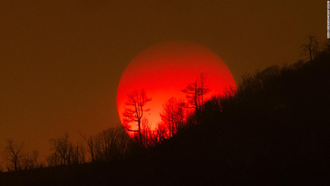 The sun sinks behind a smoky sky and burned forest near Mariposa on Sunday, July 24.