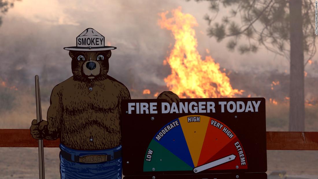 Fire burns near a Smokey the Bear warning sign on Sunday.