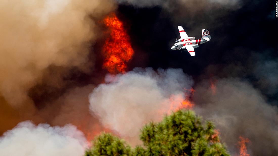 An air tanker flies past flames while battling the Oak Fire in Mariposa County on Sunday.