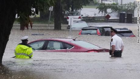 Police wade through floodwaters looking for those in their cars on Tuesday, July 26, 2022.