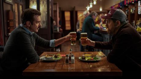 Ted Lasso (Jason Sudeikis) shares a toast with Coach Beard (Brendan Hunt) at the Crown &amp; Anchor in an episode of &quot;Ted Lasso.&quot;