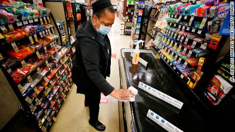 A grocery cashier sanitizes a checkout lane. The pandemic has created more tasks at work and at home.