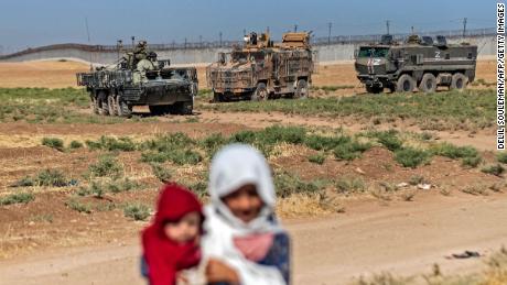 Syrian children stand near military vehicles during a joint Russian-Turkish patrol in the countryside, near the border with Turkey in Syria&#39;s northeastern Hasakah province on July 28.
