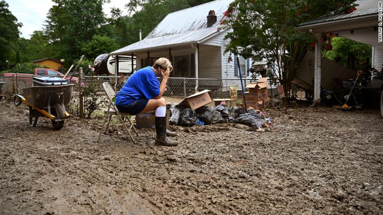 Teresa Reynolds sits exhausted as members of her community clean the debris from the flood ravaged homes at Ogden Hollar in Hindman, Kentucky on Saturday, July 30.