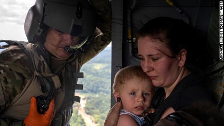 Command Sgt. Major Tim Lewis of the Kentucky National Guard secures Candace Spencer, 24, while she holds her son Wyatt, 1, after being airlifted on July 30, 2022, from South Fork, Breathitt County, Kentucky. 