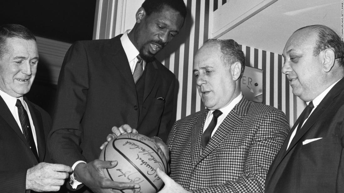 Russell, center left, and Auerbach look over an autographed ball after Russell was named Boston&#39;s head coach in 1966, making him the first Black head coach in NBA history.