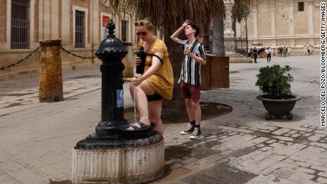 Visitors use a public fountain in Seville, Spain.