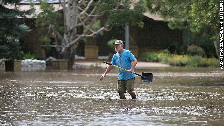 A resident of Flagstaff, Arizona, works to protect homes from flood waters that turned a cul-de-sac into a small lake, July 27, 2022.