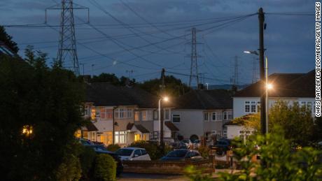 Electricity transmission towers near residential houses with lights on in Upminster, UK, on ​​Monday 4th July 2022. The UK will water down one of its key climate change policies as it fights rising energy prices that have contributed to the cost of - life crisis for millions of consumers. 