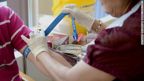 A nurse ties a tourniquet before taking blood at the Temple Fortune Health Centre GP Practice near Golders Green, London.