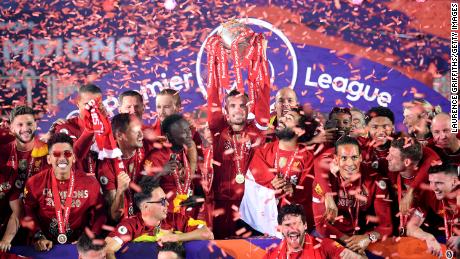 Jordan Henderson lifts the Premier League trophy alongside Mohamed Salah as they celebrate their league win.