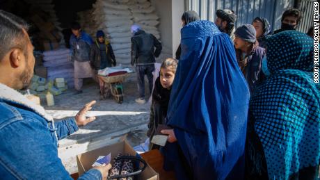 یک زن افغان جیره ماهانه غذاهای اصلی خانواده اش را از یک نقطه توزیع برنامه جهانی غذا در منطقه جی رئیس در غرب کابل جمع آوری می کند.