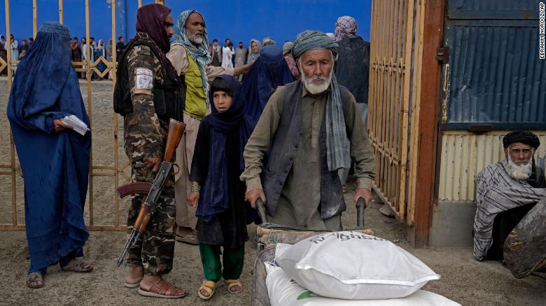 A Taliban fighter stands guard as people receive food rations distributed by a South Korean humanitarian aid group, in Kabul, Afghanistan. 