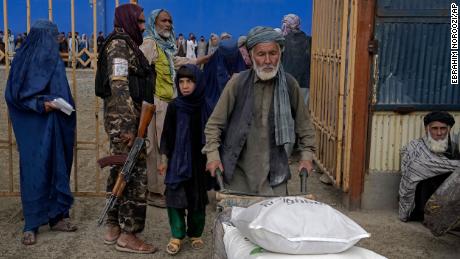 A Taliban fighter stands guard to receive food rations distributed to people by a humanitarian aid group in Kabul in May 2022. 