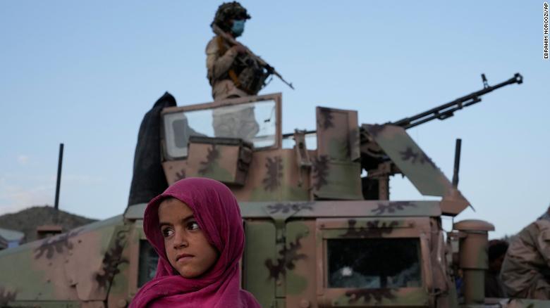 An Afghan girl stands by a Taliban fighter in Paktika province, Afghanistan, Saturday, June 25, 2022. 