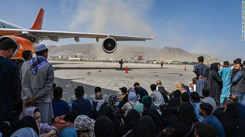 Afghan people sit as they wait to leave the Kabul airport in Kabul on August 16, 2021, after a stunningly swift end to Afghanistan&#39;s 20-year war. 