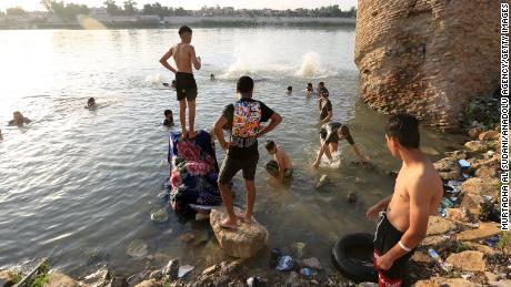 People cool off by the Tigris River in hot weather in Baghdad, Iraq, on August 4.