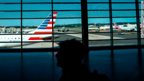 A traveler walks past American Airlines planes gated at Ronald Regan Washington National Airport on July 11, 2022 in Arlington, Virginia. Staffing shortages, the COVID-19 pandemic and other issues have led to historic levels of disruptions in U.S. air travel.