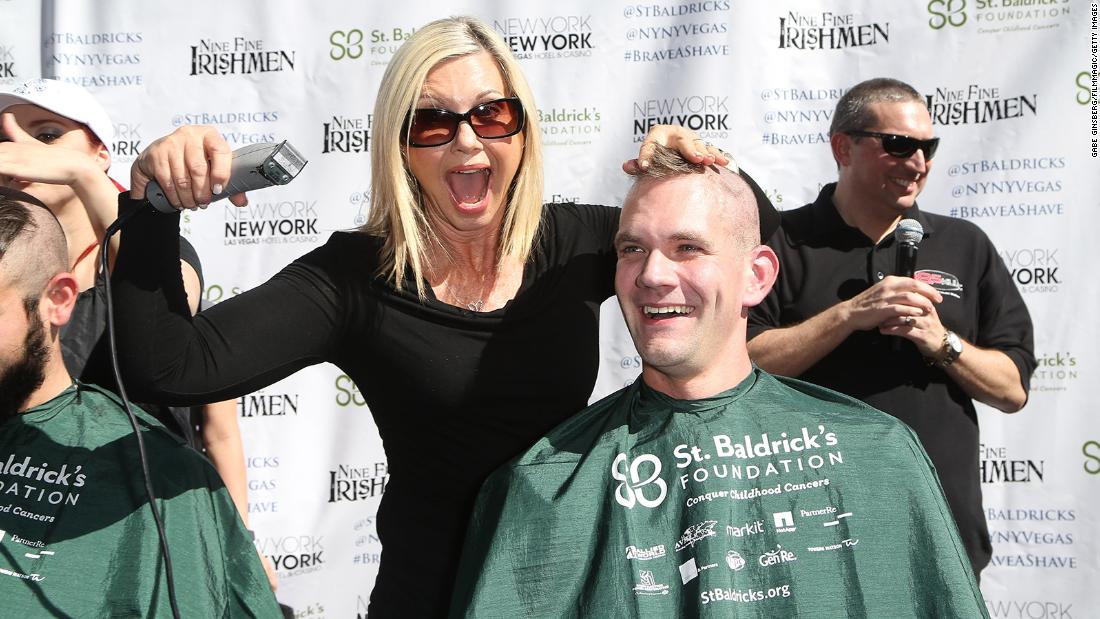 Newton-John shaves the head of Greg Chase, director of guest experience at the New York-New York Hotel &amp;amp; Casino, during a fundraiser in Las Vegas in 2015.