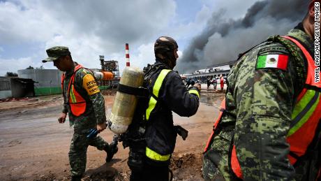 Mexican and Cuban firefighters work to put out the fire at the fuel depot that was sparked by a lightning strike.