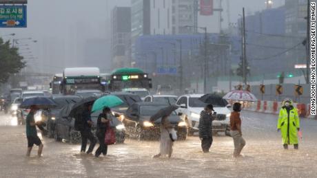 Pedestrians cross a flooded road in Jimbo, Seoul on August 9.