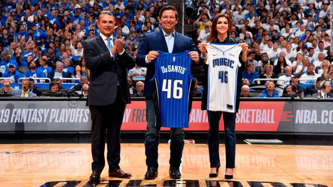 DeSantis and his wife hold up Orlando Magic jerseys before an NBA playoff game in April 2019.