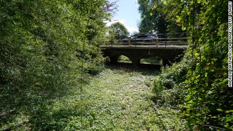 A car drives over a bridge over a dry riverbed where the River Thames normally flows, near Kemble in Gloucestershire.