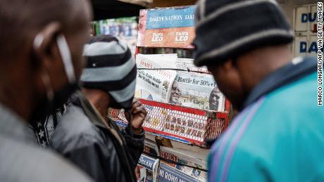 Moradores olham para jornais exibidos em um estande em Mathare, Nairóbi, em 12 de agosto de 2022, após as eleições gerais do Quênia. 