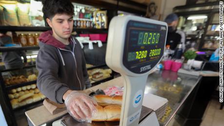 A young salesman weighs buns in a store on August 10, 2022, Argentina, Buenos Aires.